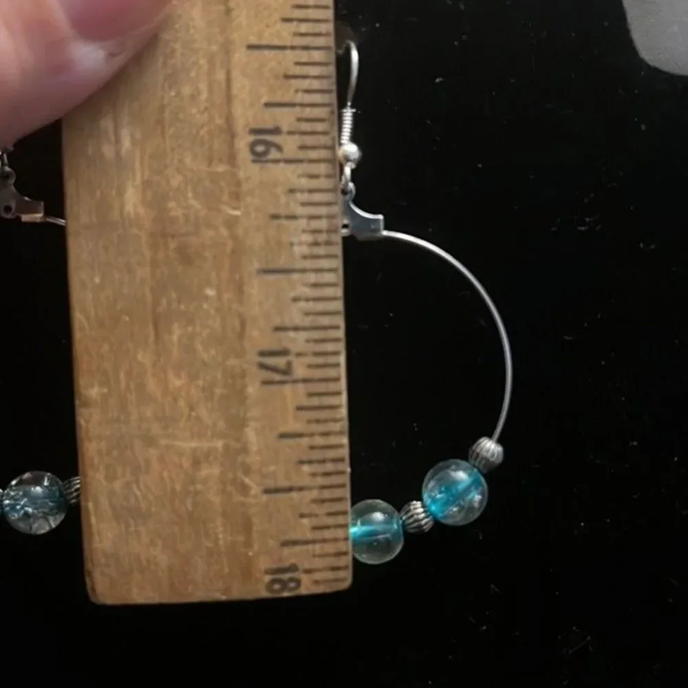 Handcrafted silver tone hoop earrings with clear and blue beading.